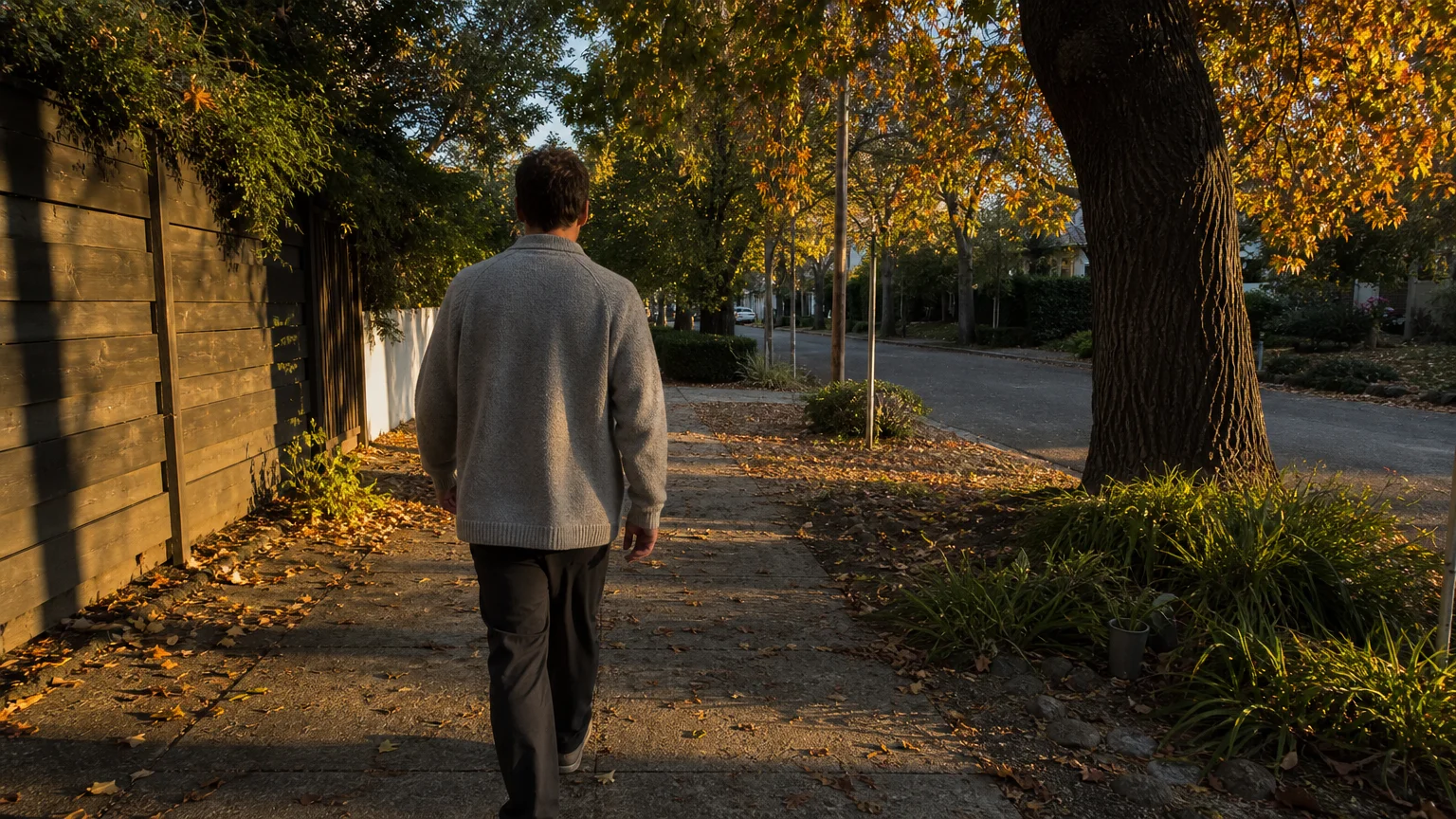 A person in a knit sweater takes a peaceful walk down a sun-dappled path lined with autumn trees, showcasing post-meal movement.